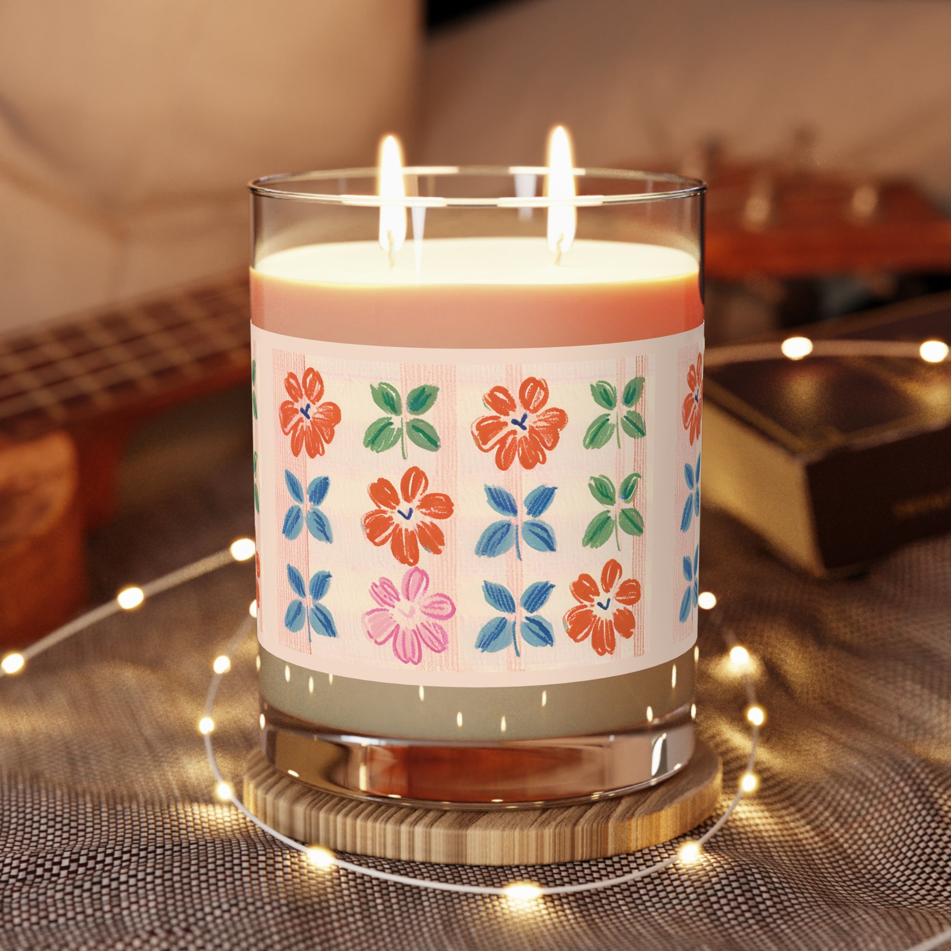 100 % Vegan Soy wax, Glass Jar Candle with two Cotton Wicks. It features a color pencil Plaid floral print in green, grey blue, orange, and pink, hues, set against a peach color backdrop  