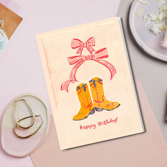 Make someone's birthday extra special with our adorable&nbsp;western and coquette aesthetic themed folded card! It features playful cowboy boots, red-pink bows and elegant handwritten Happy Birthday calligraphy, all in vibrant colors. Perfect for the birthday girl who loves a touch of sass and elegance.
